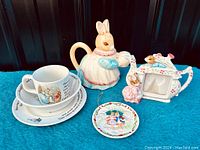 Full view showing all items: Wedgwood Peter Rabbit tea set, ceramic bunny teapot, Schmid bunny figurine, decorative plate ornament.