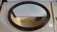 Top view of the oval mirror showing overall shape and wood frame finish with a ruler for scale.
