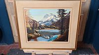 Framed oil painting of snow-capped mountain and lake with a wood and gold trim period frame.