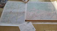 Two maps laid out on a table, one larger map with a ruler to show scale.