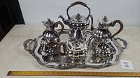 Full view of the 7-piece silver plated tea set arranged on the ornate tray with a measuring ruler showing tray size.