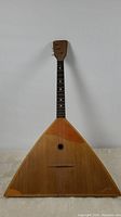 Full view of the vintage 3-string balalaika with triangular body and wooden neck.