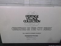 Photo of Heritage Village Collection box label indicating item as All Saints Corner Church in Christmas in the City Series, handpainted porcelain.