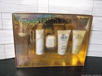 Front view of sealed White Diamonds by Elizabeth Taylor 6-piece gift box set with holographic gold packaging showing 5 plus 1 free products inside.