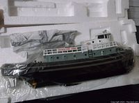 Texaco Fire Chief Tug Boat wrapped in protective plastic, predominantly black and dark green with white railings, labeled 'TEXACO FIRE CHIEF'.