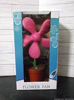 Photo of the fan inside its packaging showing the pink flower fan with pot base and USB or AC/DC power compatibility labeled on box.