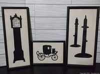 Three framed felt silhouette artworks arranged together showing a grandfather clock, horse carriage, and candlesticks.