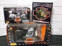 Photo showing all three Harley Davidson items including 1:10 Heritage FLSTS model, 1:18 Police motorcycle model and boxed ornament