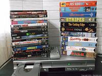 Used DVDs, VHS tapes and remote control stacked on Samsung DVD/VHS player