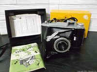 Full view of the Kodak Tourist folding camera with bellows extended, original yellow box and instruction manual included.