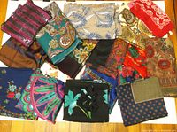 Photo showing a group of 18 assorted vintage women's scarves with different colors and patterns, laid out on a wooden surface.