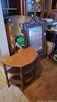 Photo showing the ornate antique mirror with carved wooden frame leaning against a wall and the halfmoon side table placed in front of it.
