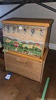 Wood and tole painted bread boxes stacked, showing scenic grapevine and countryside painting on the top box and natural wood drawer below