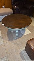 Full view of round coffee table showing dark wood top with scratches.