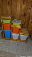 Front view of pine wood storage stand with various colorful plastic storage tubs inserted