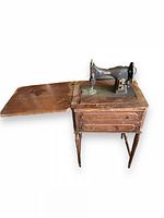 Full view of antique Domestic rotary sewing machine mounted on wooden table with fold-out extension and turned legs