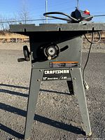 Front view of Craftsman table saw showing blade height adjustment wheel, model label on frame, and power cord
