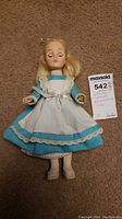 Effanbee Storybook Alice in Wonderland doll lying on carpet, wearing blue dress with white apron and shoes, tag next to doll