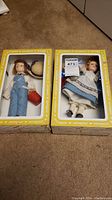 Pair of Effanbee Storybook Jack and Jill collectible dolls in original yellow and white branded display boxes on carpeted floor.