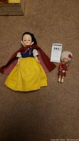 Effanbee Storybook Snow White doll next to small bagpipe doll shown on carpeted floor