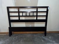 Front-facing photo of the queen size headboard showing the geometric rectangular open panel design in very dark brown wood.