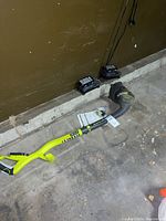 Ryobi EasyEdge edger with two batteries and charger on concrete floor in garage.