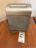 Front view of silver Fellowes Shredmate small desktop shredder showing mesh metal basket and power cord coiled around it.