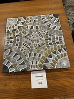 Front view of the square acrylic painting showing intricate abstract pattern in black, white, and gold.