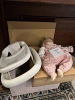 Porcelain doll in floral pink outfit and play walker in box from an above angle.