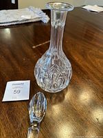Crystal cut glass decanter with bulbous base and detailed floral and geometric cuts. Matching stopper shown separately on table.