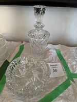 Photo showing a vintage RTL hand cut crystal decanter with stopper along with two crystal ashtrays, all clear intricately designed.