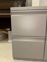 Front view of light gray metal file cabinet with two drawers, closed.