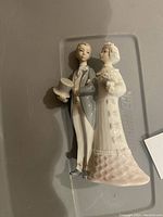 Side view of Lladro wedding couple figurine showing details of groom holding top hat and bride in wedding dress with bouquet.