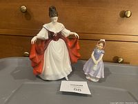 Photo showing both Royal Doulton figurines, 'Sara' and 'Ivy' side by side on a gray surface against a wood background.