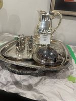Large silver tray holding the salt and pepper shakers, water pitcher, and covered dish, showing ornate detailing and condition