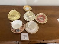 Top view of china teacups with saucers arranged on wooden surface