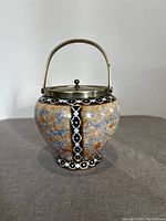 Antique barrel style biscuit jar with metal lid and handle shown from front, clearly displaying the detail pattern and shape.