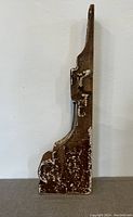 Side view of the antique wooden corbel showing its height profile, chipped paint and carved detailing.