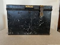 Closed black metal box with visible wear and scratches.