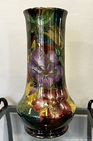 Front view of antique Maling porcelain vase showing purple and red floral artwork with gold highlights on reflective dark background