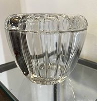 Side view of the clear cut glass container showing vertical ridge design and lid fitting over the body.
