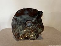 Photo showing whole pottery serving dish with organic shape, glossy multi-tonal glaze, textured and patterned surface details.