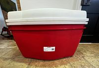 Side view of stacked red and white plastic storage totes showing size and condition.