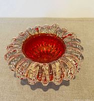 Top-down view of heavy MCM vintage hand blown art glass vessel with fire red center, gold flecks, and clear bubble textured edge.