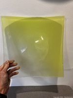 Square clear glass serving platter with yellow ombre effect held showing the curved shape and color gradient from yellow to clear.