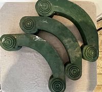 Top view of three antique wooden corbels with green paint showing the curved shape and circular carved ends.