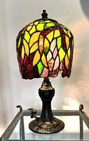 Full view of stained glass table lamp with colorful handmade shade and brass-toned ornate base.