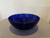 Side angle showing the rounded deep cobalt blue glass bowl with reflective glossy surface.
