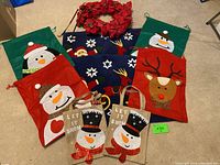Christmas-themed door mats with snowman, reindeer, and Santa designs, small burlap gift bags, and red poinsettia wreath.