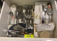 Cutlery, utensils, linens including forks, knives, spoons, towels, bun warmer in kitchen drawer.